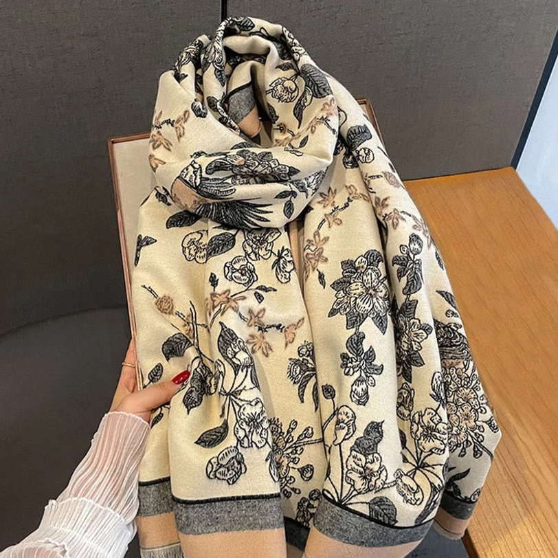 Close-up detail view of Tibetan rose and bird printed scarf with grey trim on wooden surface
