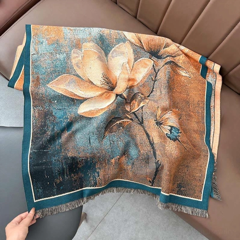 Tibetan handwoven scarf draped on brown leather sofa, orange teal vintage magnolia butterfly print detail