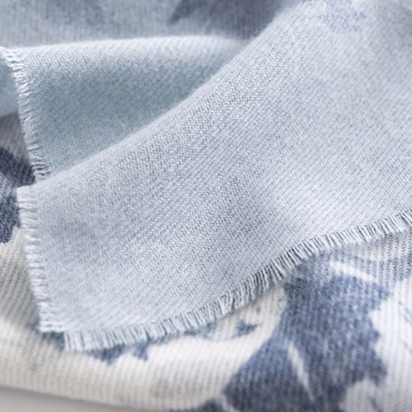 Light sky blue Tibetan scarf fabric close-up showing frayed raw hem edge details and smooth warm woven textile surface