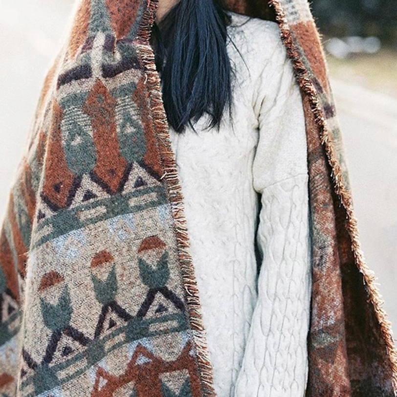 Tibetan scarf wrap with frayed hem and warm geometric prints paired with knit sweater, rear upper body portrait on outdoor roadside