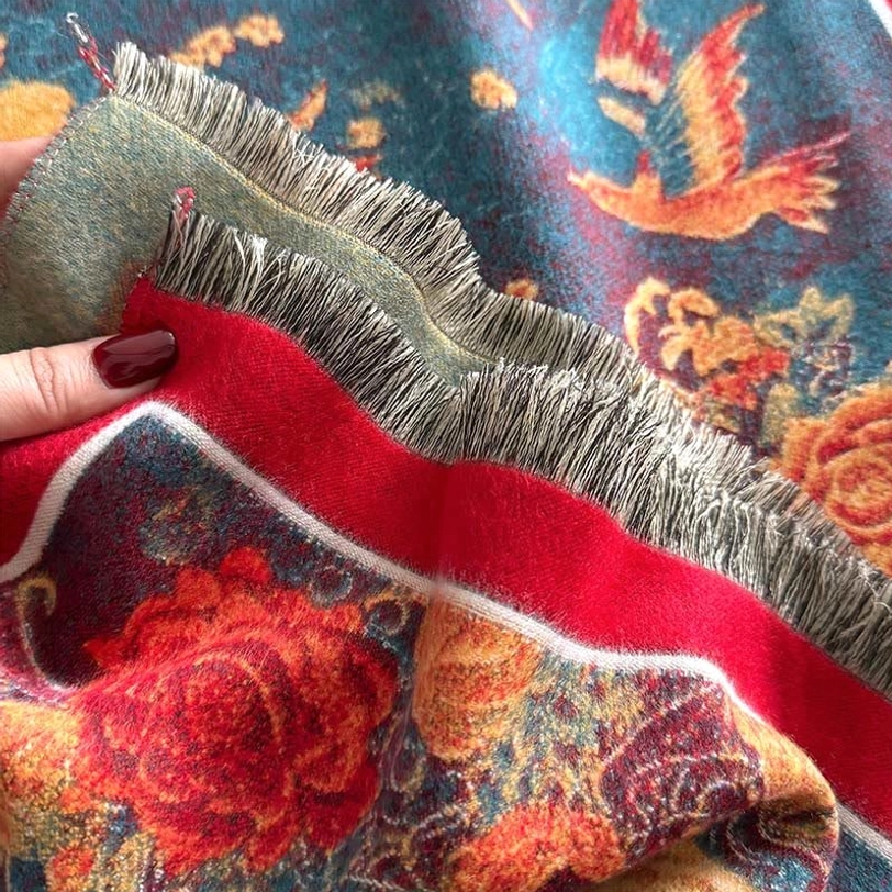 Extreme close-up of Tibetan scarf tassel hem showing frayed edges soft pile texture and vibrant floral bird prints