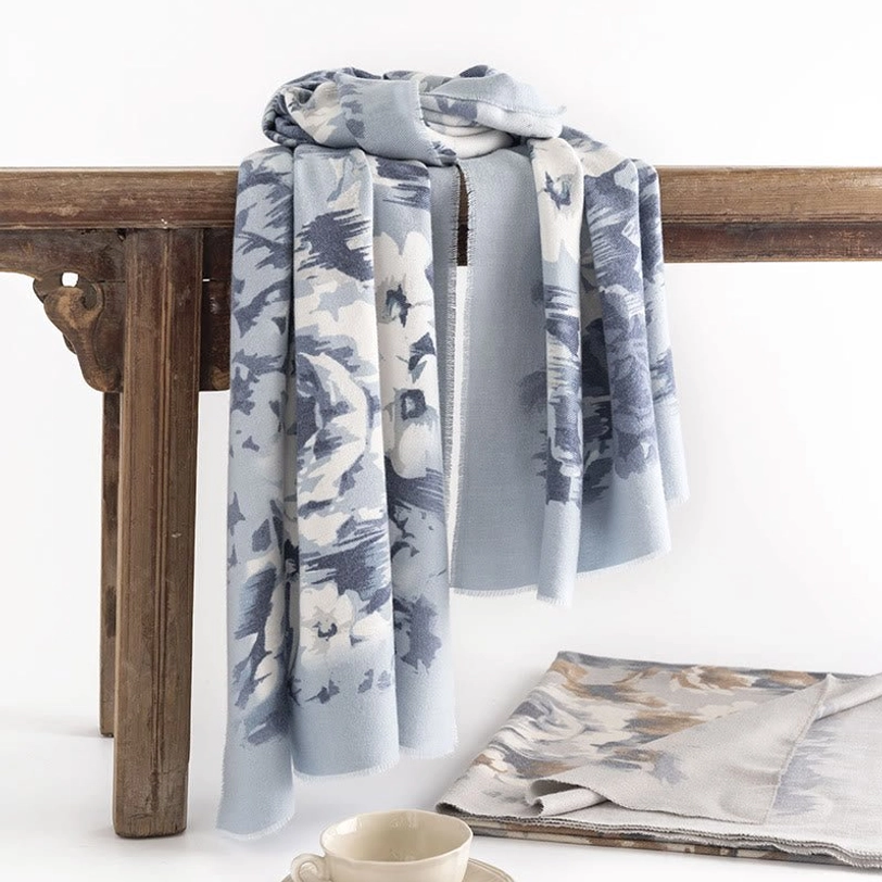 Tibetan floral scarf wrap with blue-white abstract pattern displayed on vintage wooden table, side angle view showing soft woven fabric texture