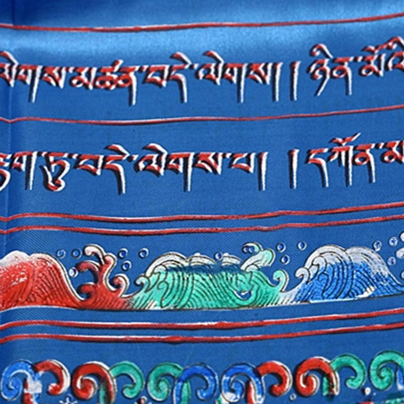 Close-up detail of Tibetan script and prayer text patterns on khata scarf with red border lines and wave motifs on satin fabric