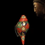 Tibetan sacred shankha conch shell with Buddha medallion and turquoise inlay, side view showing gold mantra engravings