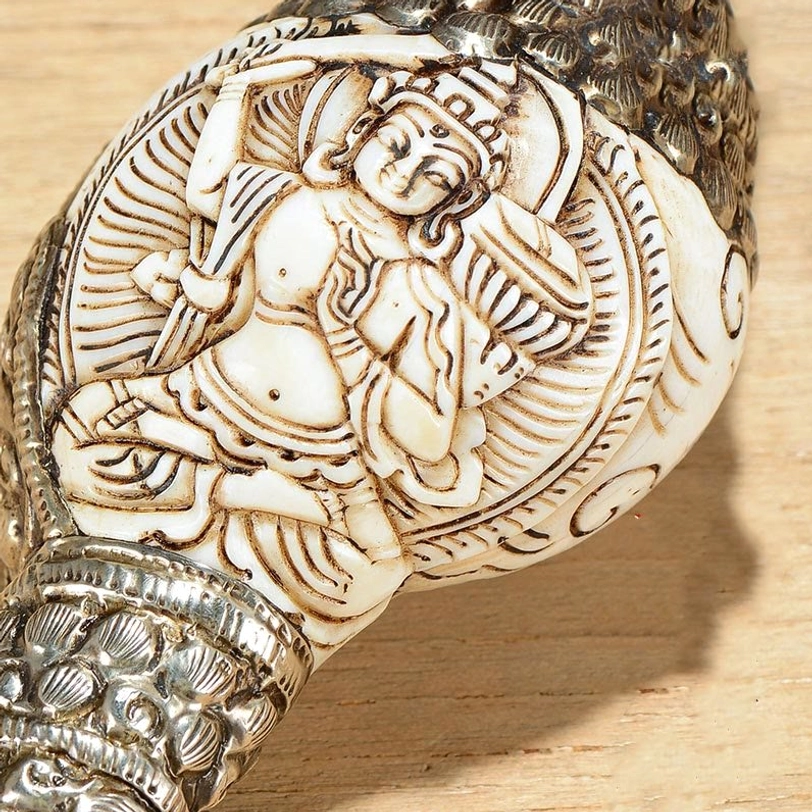 Close-up detail of Tibetan conch Buddha carving with exquisite relief engraving and silver trimmed border