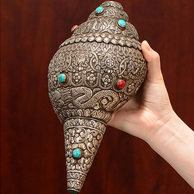 Hand-held Tibetan shankha conch shell demonstrating size and hand-carved details with turquoise gemstone inlays, side view