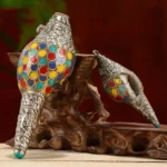 Tibetan handcrafted shankha conch shell with colorful inlays on wooden display stand and dark red backdrop