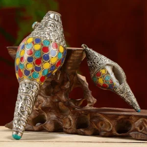 Tibetan handcrafted shankha conch shell with colorful inlays on wooden display stand and dark red backdrop