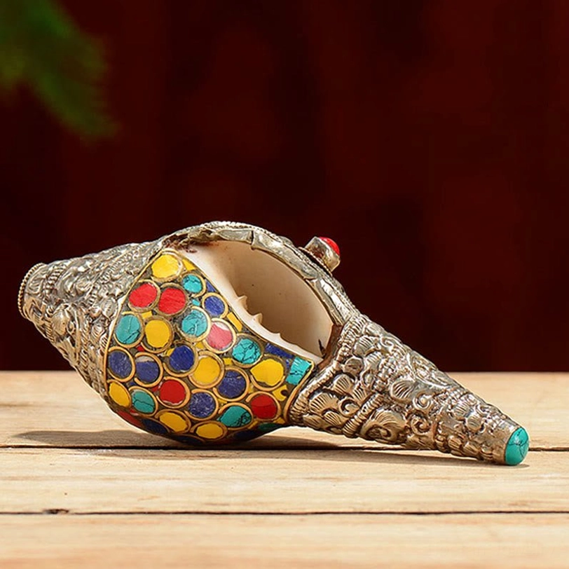 Open-mouthed Tibetan shankha conch shell displaying interior cavity and colorful stone inlays