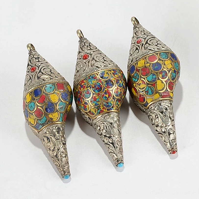 Detailed view of Tibetan shankha conch shell terminal showing red gemstone inlay and elaborate scroll silver carvings