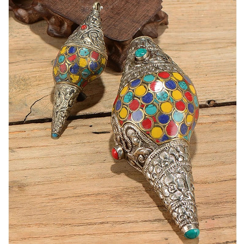 Side view of Tibetan shankha conch shell showing silver floral embossing and turquoise gemstone accent