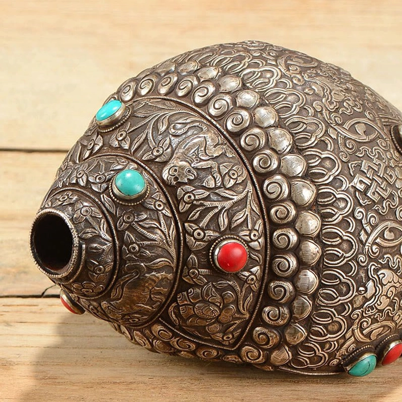 Close-up of shankha conch shell mouth opening showing circular blow hole and intricate auspicious symbol carvings, front detail view