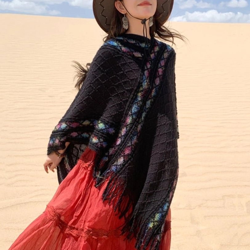 Black tassel poncho shawl back three-quarter view in desert landscape paired with red long skirt