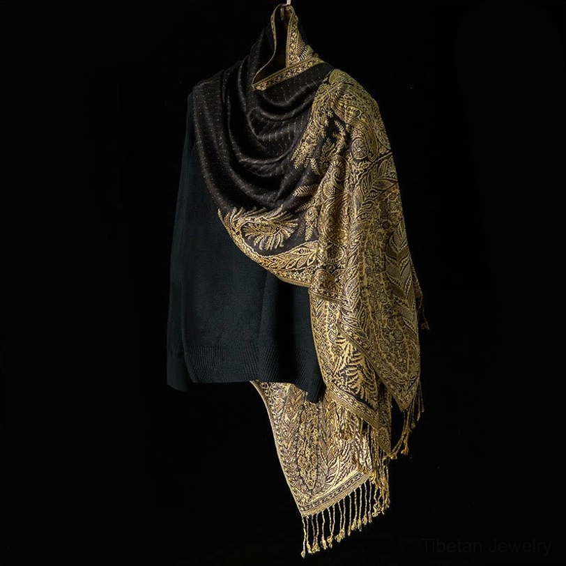 Black base Tibetan shawl with ornate gold floral motifs and long tassel trim, three-quarter side view