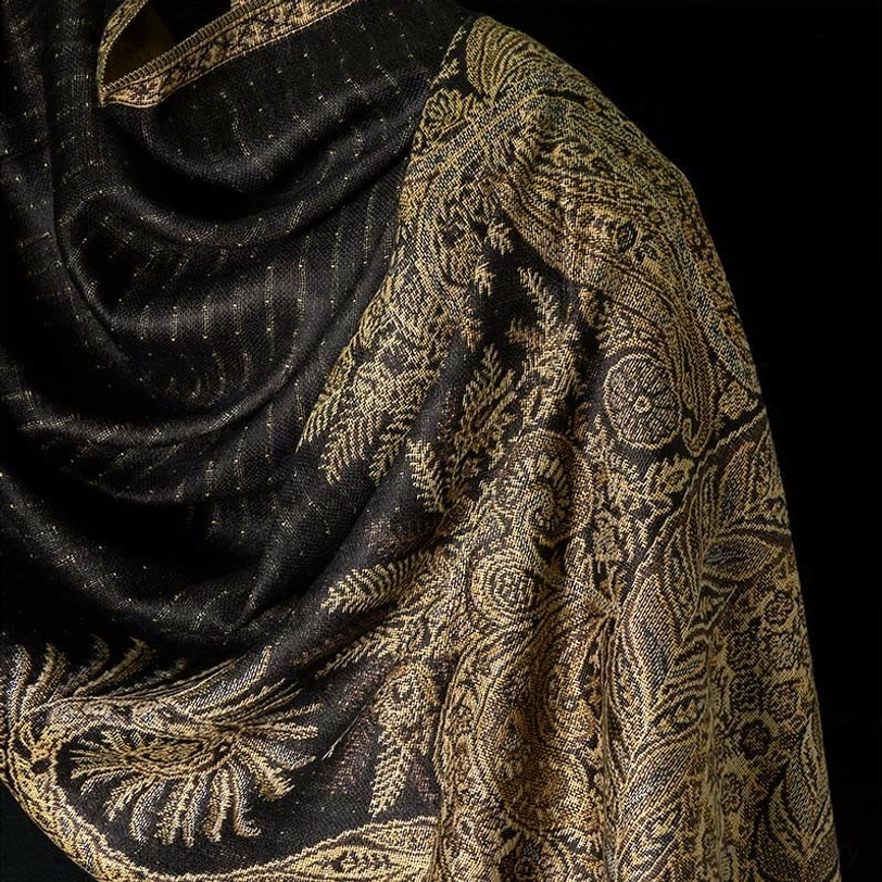 Detailed close-up of black Tibetan shawl showing intricate gold woven floral designs and subtle dotted fabric texture