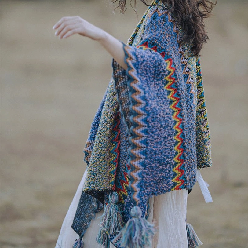 Side angle view of blue ethnic knitted shawl with contrast chevron border and decorative tassel accents