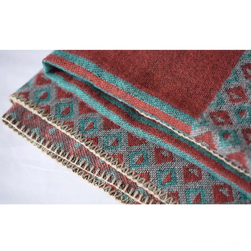 Folded Tibetan shawl edge close-up showing multi-layer patterned border with decorative blanket stitch and repeating diamond motifs