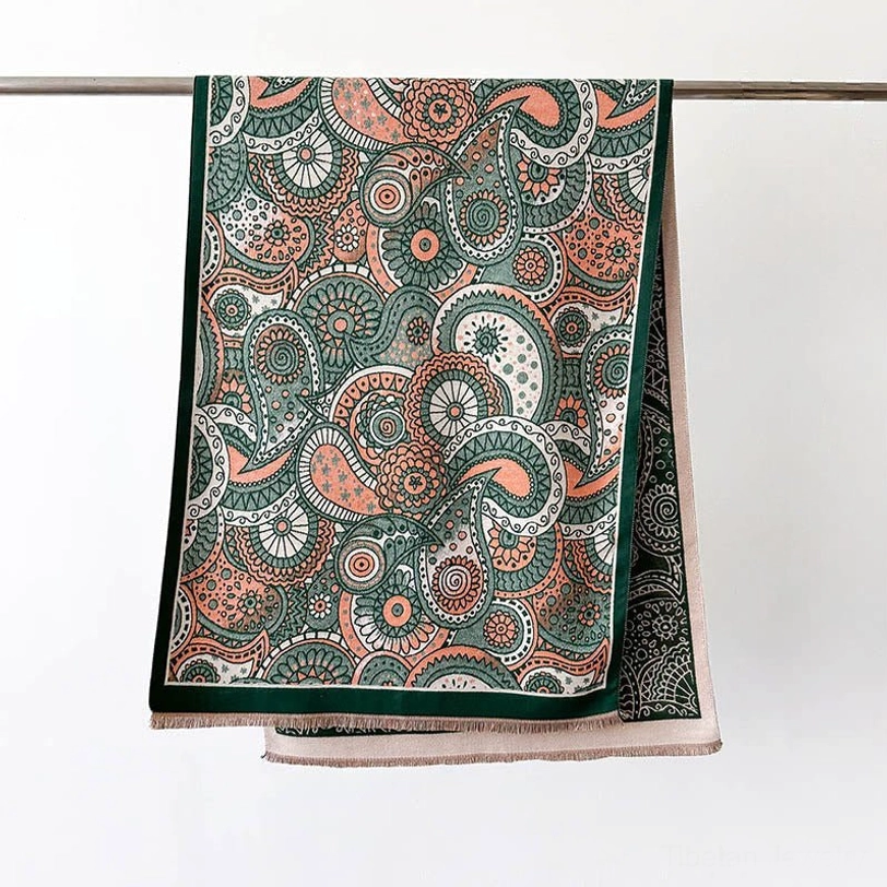 Tibetan ethnic shawl hanging display with dark green border trim on white background, showcasing earthy color palette and reversible design