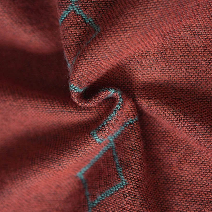 Close-up detail of Tibetan shawl fabric showing rust base with teal diamond pattern, dense woven jacquard texture and geometric motifs