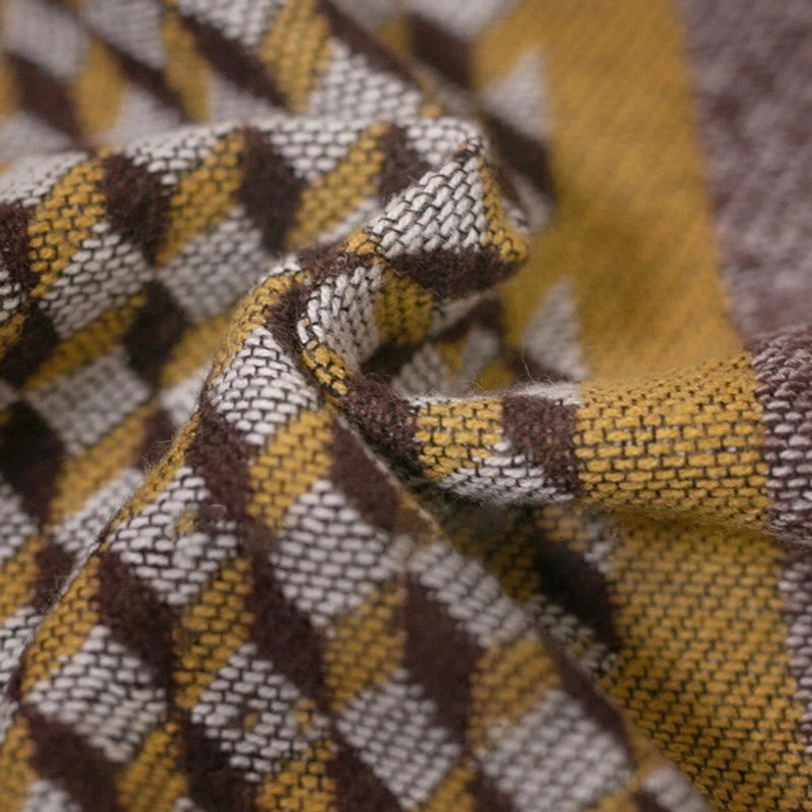 Flat lay close-up of Tibetan poncho scarf fabric showing mixed houndstooth and stripe weave, demonstrating soft textured construction