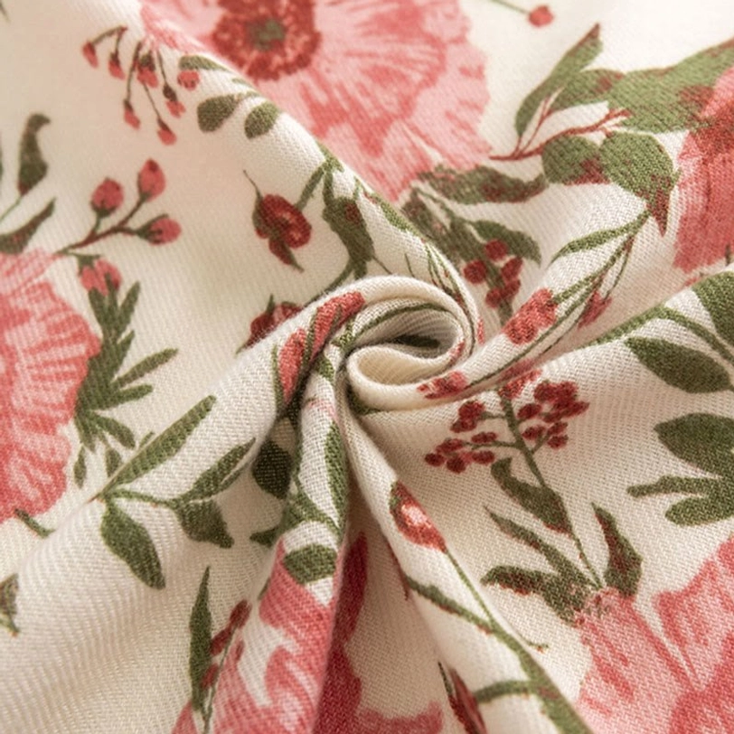 Close-up macro shot of Tibetan shawl fabric texture showing soft drape and detailed pink floral green leaf print