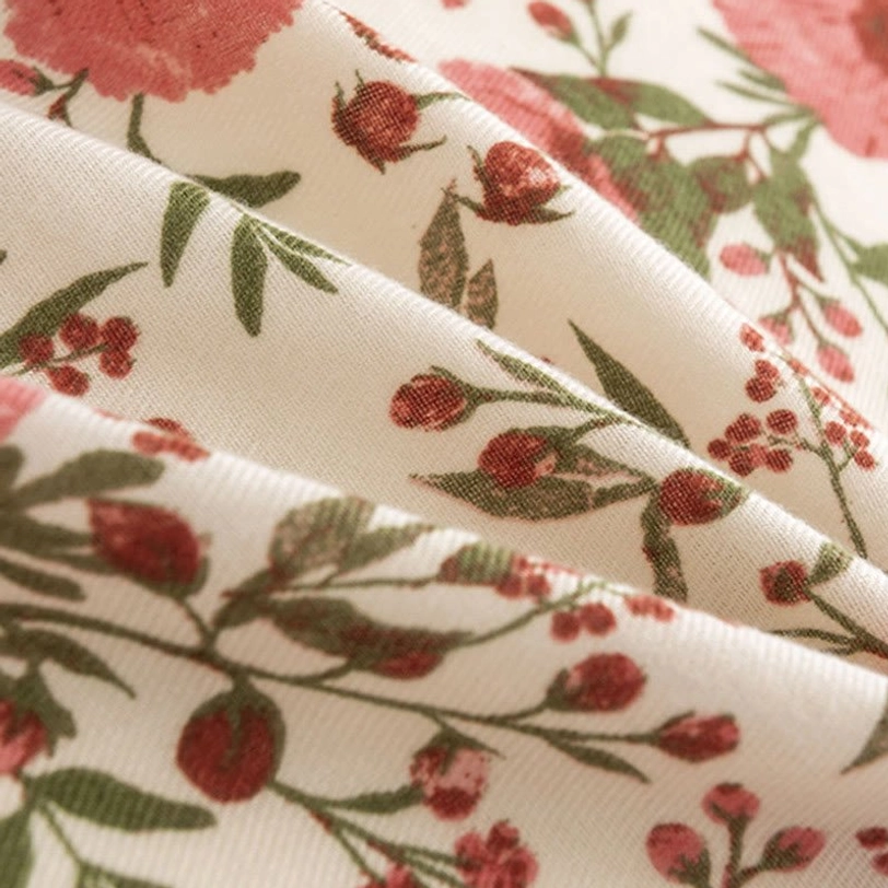 Folded Tibetan shawl close-up highlighting soft fabric texture and intricate pink flower green foliage botanical design