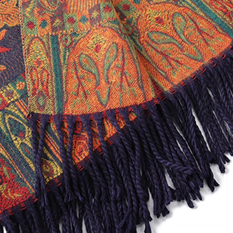 Close-up detail of shawl fringe tassels, thick woven dark blue ethnic texture with warm orange-red mixed tones, jacquard weave visible