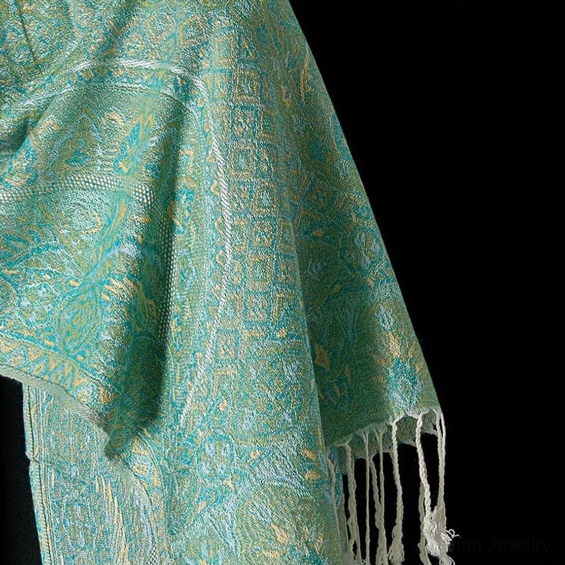 Detailed close-up of Tibetan green shawl border showing geometric jacquard pattern, delicate weave structure, and white tassel fringe