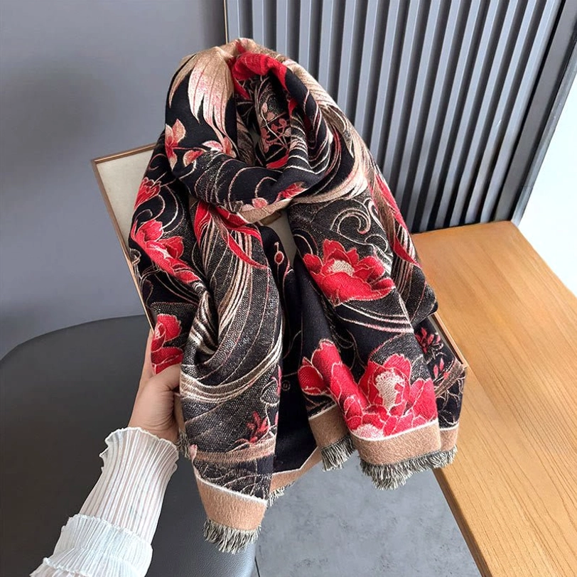 Hand-held casual view of Tibetan phoenix flower shawl on wooden surface, showcasing soft plush woven texture and red inner reversible side with tasseled hem