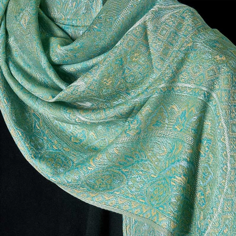 Close-up top-down view of mint green Tibetan shawl showing detailed floral woven jacquard texture and soft folded fabric drape