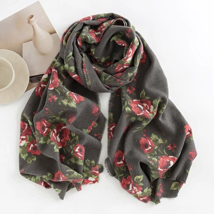 Dark gray Tibetan rose floral shawl flat laid on white surface with decorative tableware showing detailed print