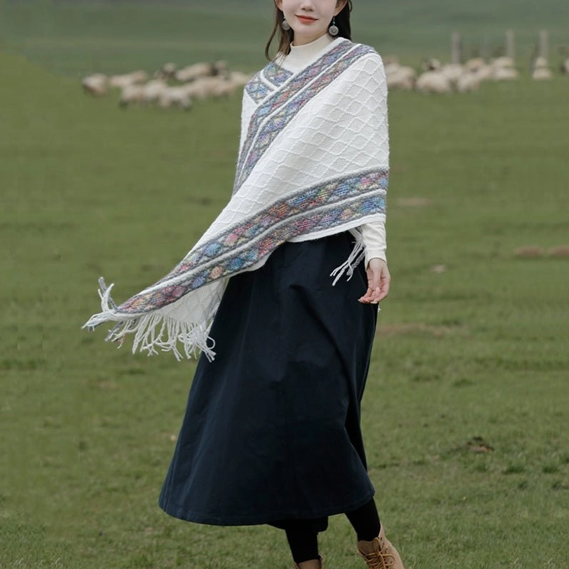 Knitted tassel shawl side view showing ethnic embroidered border and flowing tassels on grassland