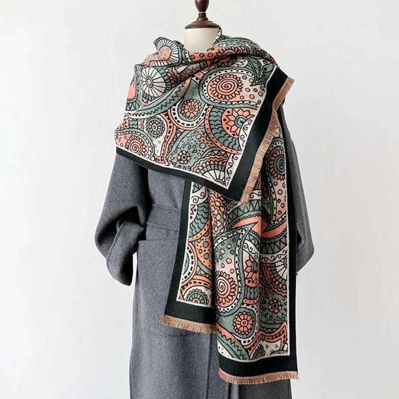Reversible Tibetan paisley shawl side view on dress mannequin paired with grey overcoat, showing geometric pattern and tassel fringe detail