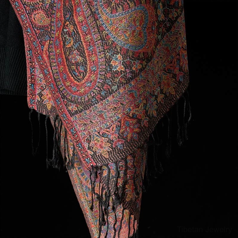 Tibetan tassel shawl bottom hem detail, showing ornate paisley borders, black tassel fringe, and handcrafted finish