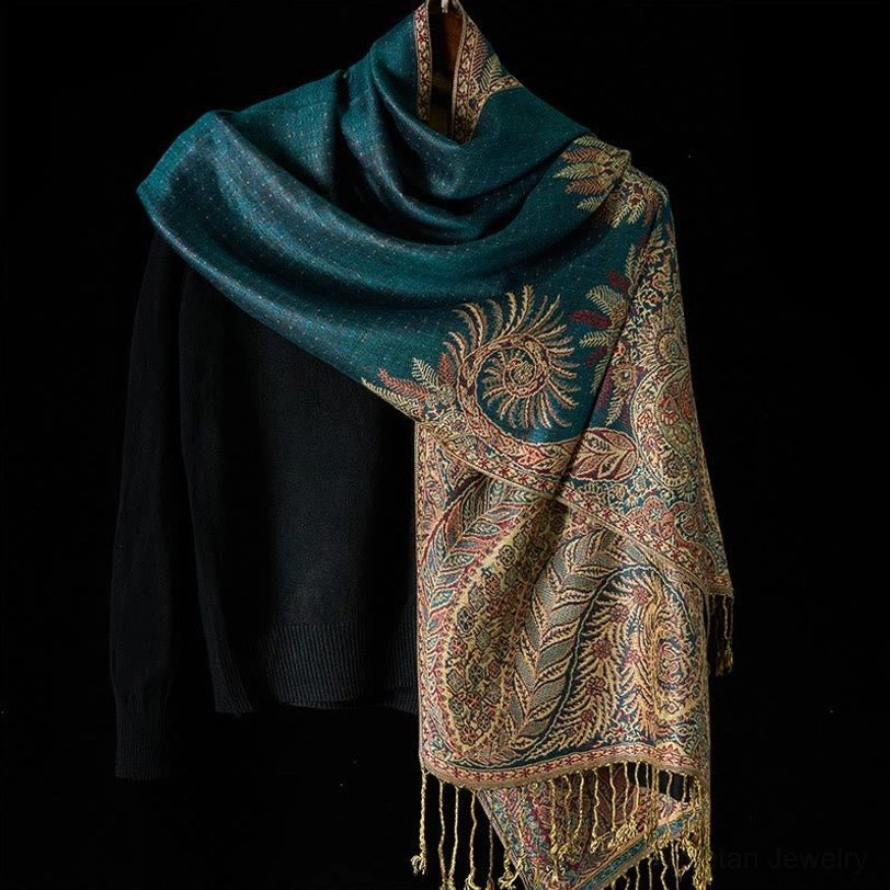 Deep teal Tibetan shawl with ornate gold paisley patterns and decorative tassel trim, styled with black knitwear