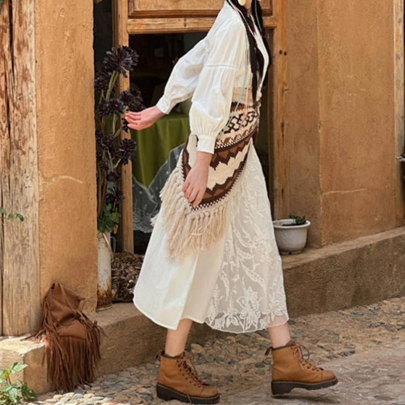 Tibetan knit shawl worn as waist sash with tassel fringe visible, side back view at adobe house exterior