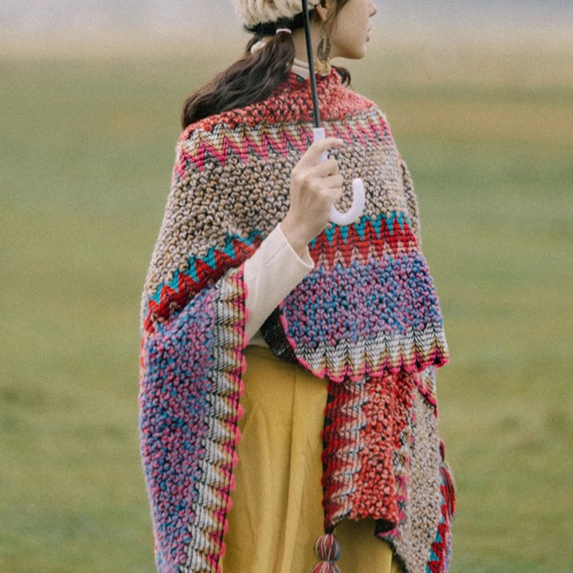 Warm knitted Tibetan wrap shawl in mixed warm tones with tassel pendants, side back view showing loose wrap drape