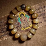 Tibetan sheep horn Om Mani Padme Hum bracelet with translucent yellow beads and dark metal spacers on Buddhist scripture background