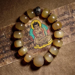 Tibetan sheep horn Om Mani Padme Hum bracelet with translucent yellow beads and dark metal spacers on Buddhist scripture background