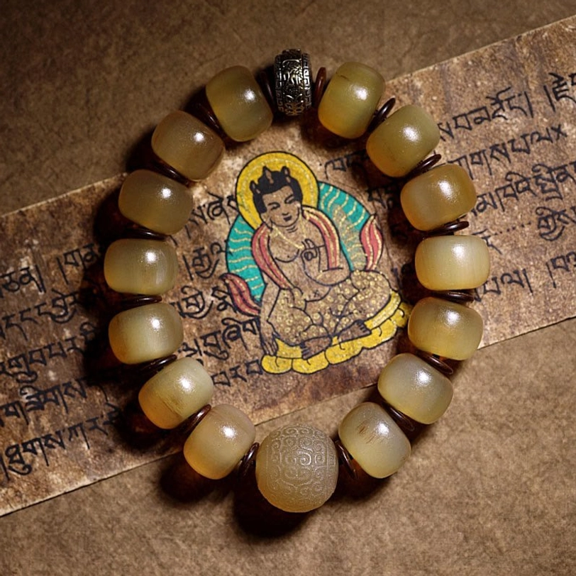 Tibetan sheep horn Om Mani Padme Hum bracelet with translucent yellow beads and dark metal spacers on Buddhist scripture background