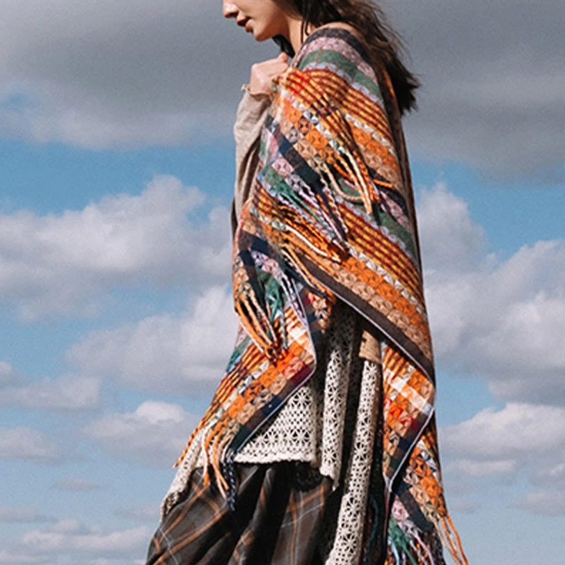 Side-back view of Tibetan tassel shawl with fringed edge and woven stripe pattern paired with lace inner garment