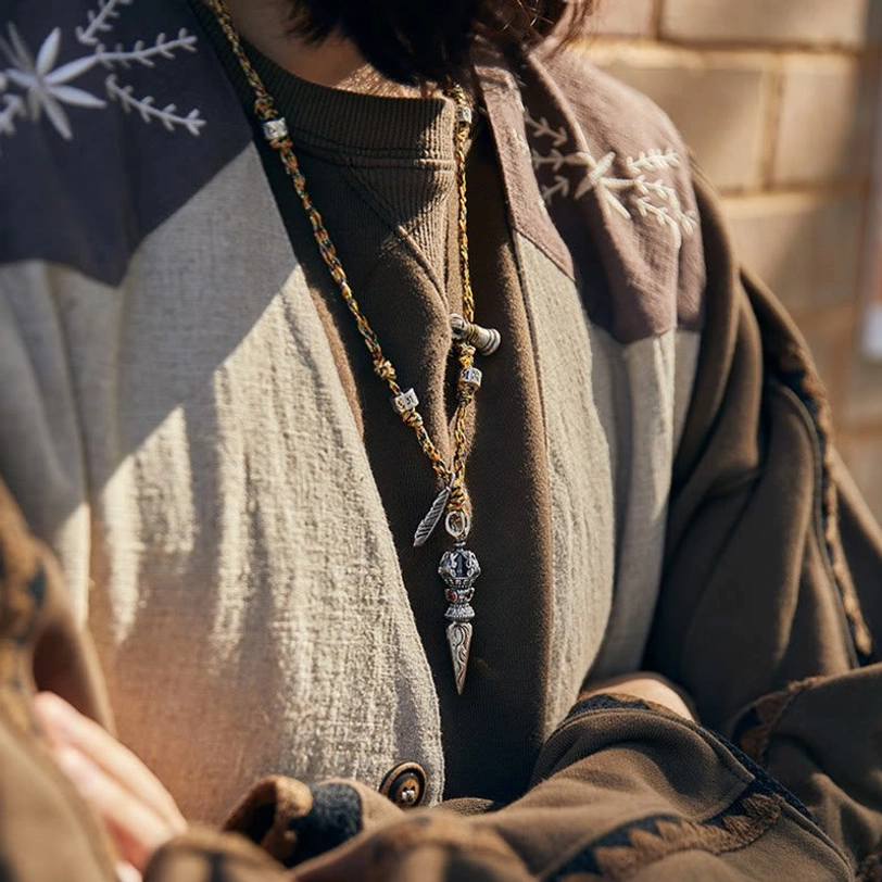 Tibetan Dorje Vajra necklace worn on body, casual on-body medium shot showing how the silver pendant sits on woven cord