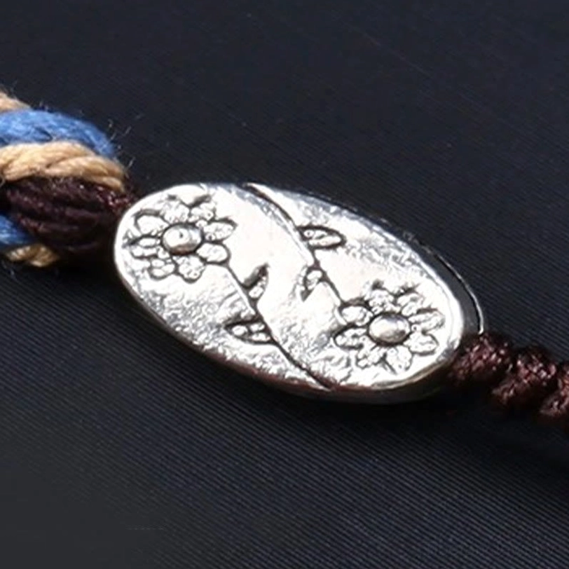 Nine-eye dzi braided necklace showing flower-carved tibetan silver ornament and multi-color woven cord