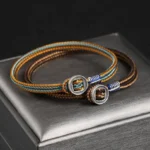 Handmade tibetan silver protection bracelet with brown and blue woven cord, silver button clasp, displayed on elegant silver jewelry box