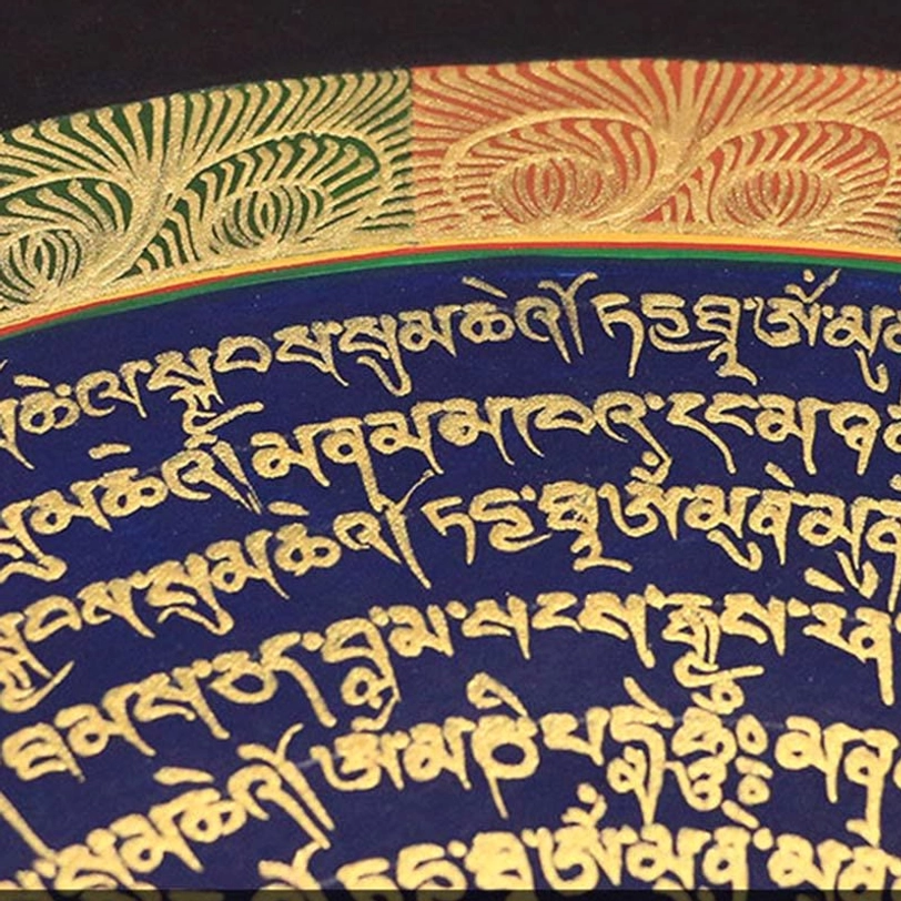 Close-up detail of dark blue Tibetan mantra thangka with intricate gold hand-painted scripture and gold leaf-style decorative patterns