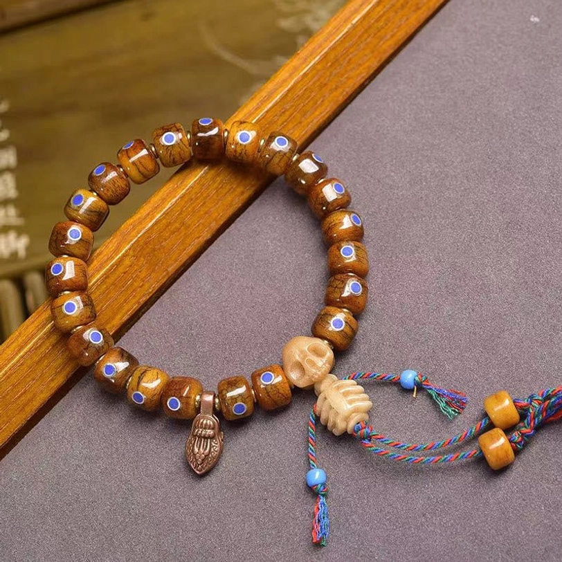 Tibetan dual skull bone bracelet with brown barrel beads and multicolor woven tassel decoration