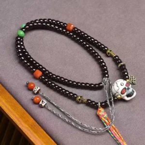 Handmade Tibetan prayer bead bracelet with eternal knot charm and woven tassel, overhead angled photography