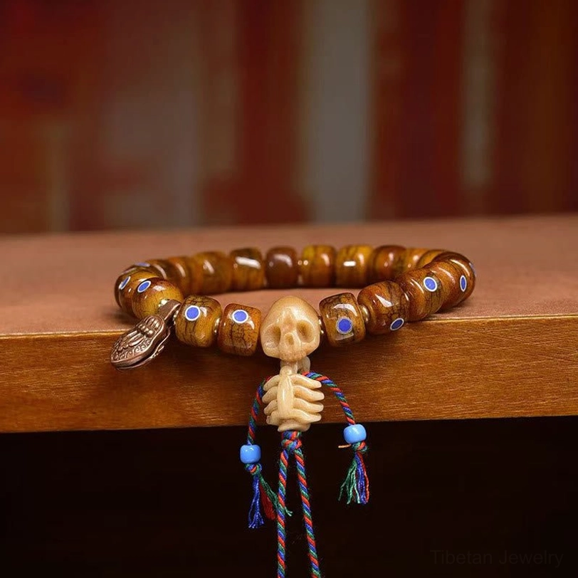 Front close-up overhead view of Tibetan skull bone bracelet with brown beads and blue pendant accents