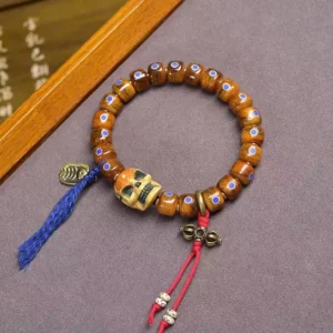 Tibetan protective bone bead bracelet with skull focal bead and colorful fabric tassel, top-down view