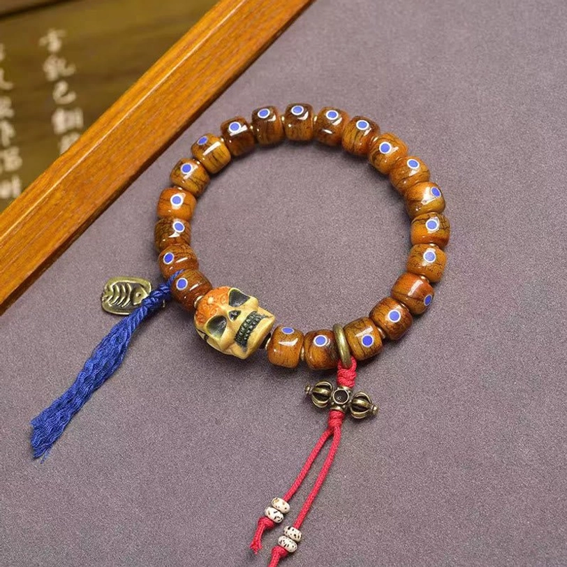 Tibetan protective bone bead bracelet with skull focal bead and colorful fabric tassel, top-down view